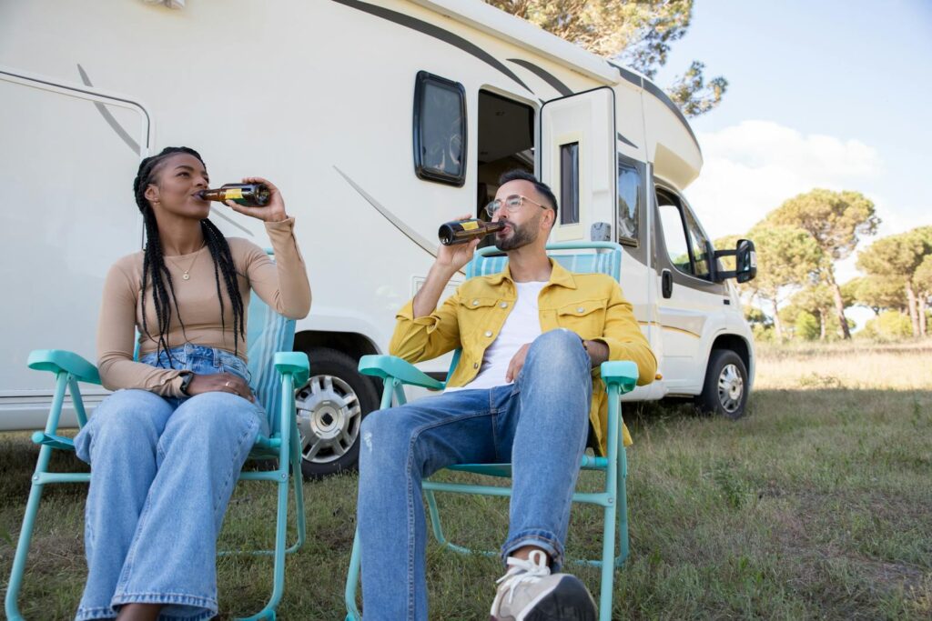 A Couple Drinking while Sitting Beside the Caravan